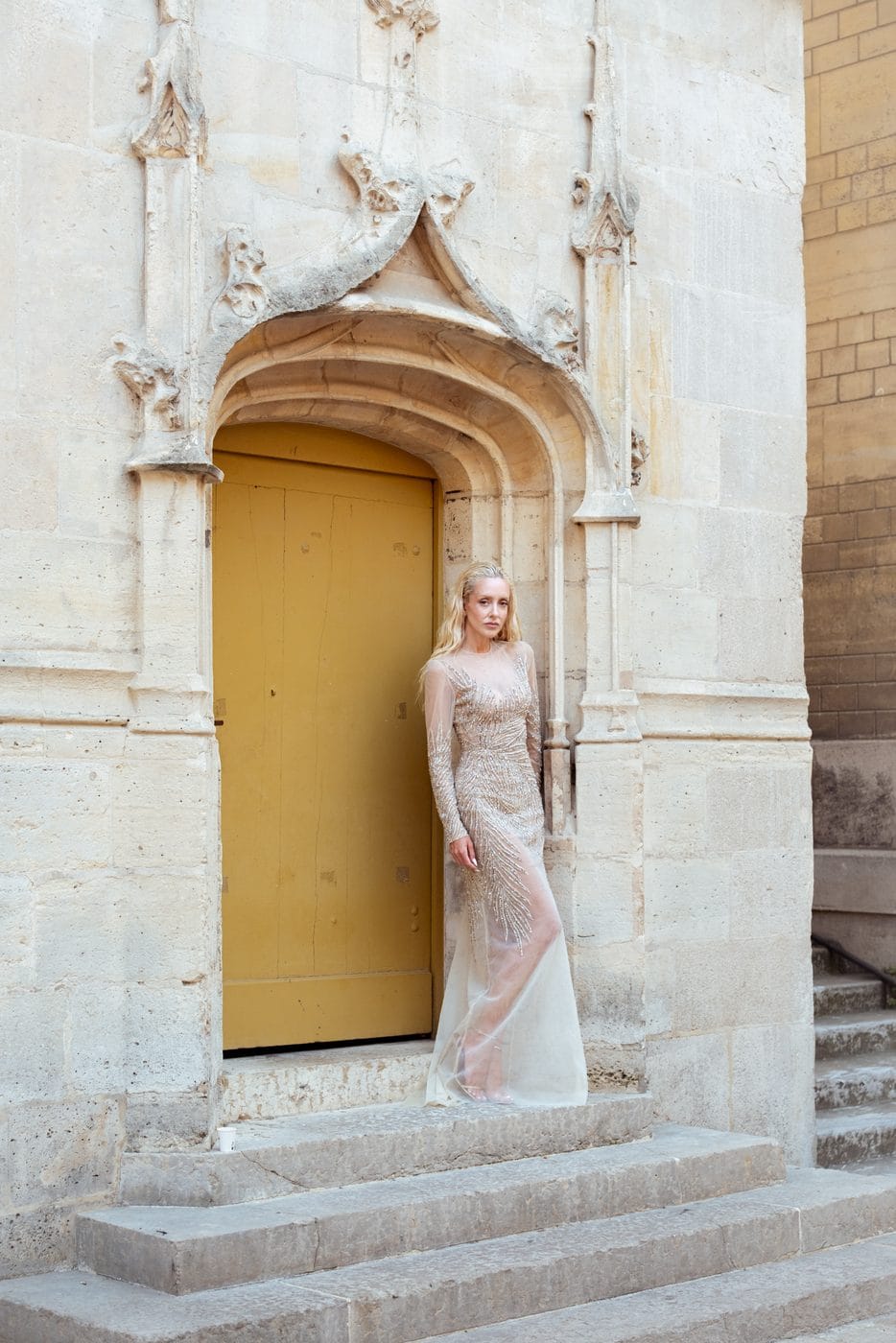 Femme en robe longue claire devant une porte dorée, Sasha Ray, Tony Ward Couture