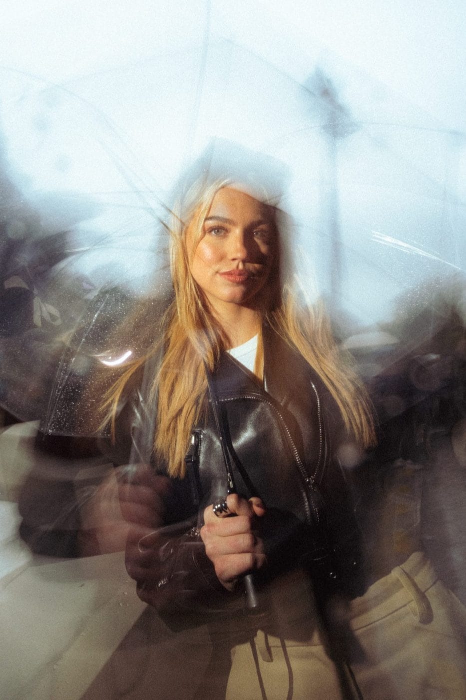 Femme blonde en veste de cuir vue à travers un reflet flou et démultiplié, Emma Brooks (@emmabrooks)
